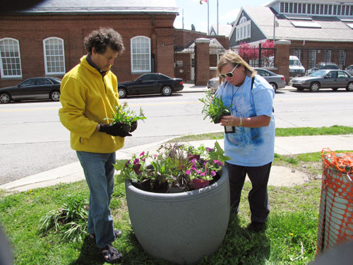 MDE employees Mike Eisner and Margie Wise plant flowers in a large outdoor flower pot on Earth Day 2009.
